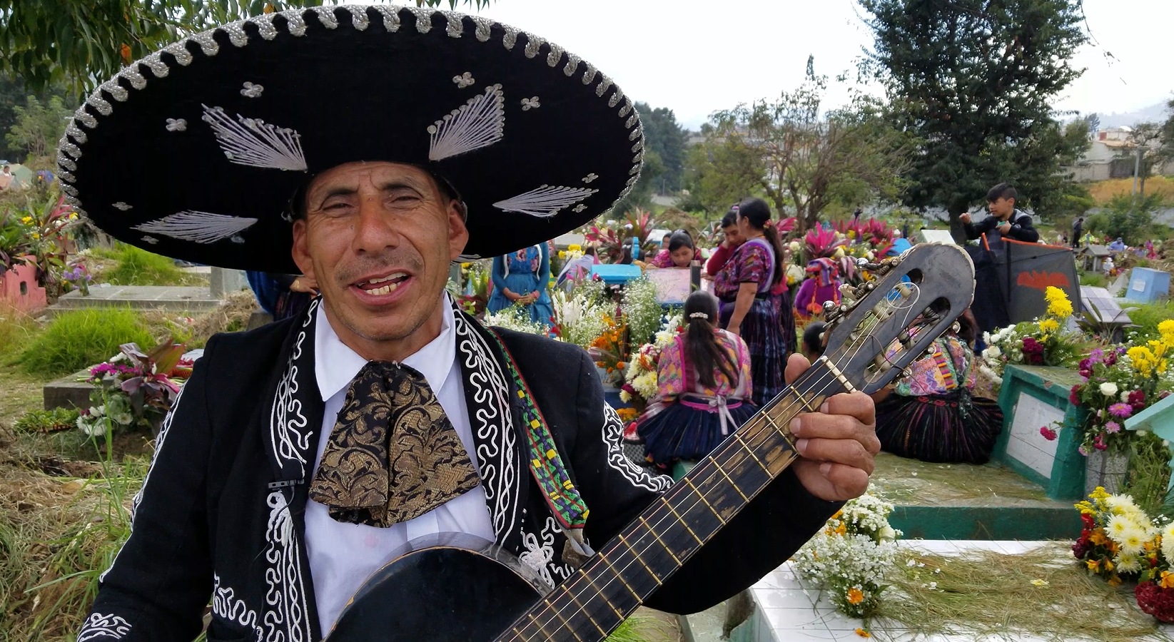 Local singer Roberto Cepeda, 65, has been playing his acoustic guitar since the age of 13. On Nov. 2, 2018, he dressed up in a traditional black Mexican mariachi suit to serenade the living and the dead during the annual Dia de los Muertos, also known as Dia de los Difuntos in Quetzaltenango (Xelaju), Guatemala's municipal cemetery.  Image by Kristian Hernandez. Guatemala, 2018.