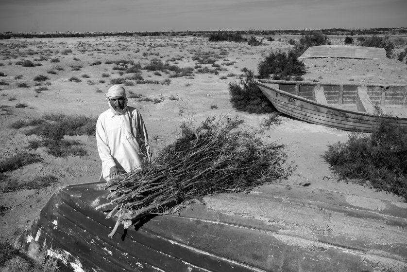 A fisherman sells tamarisk reeds in the dried-out seabed of Lake Hamoon. At the border between Iran and Afghanistan, the Sistan Basin is one of the most arid places in the world. Drought and mismanagement of irrigation has contributed to drying out the lake, impacting wildlife and the livelihood of the local population. Image by Ako Salemi. Iran, 2016.