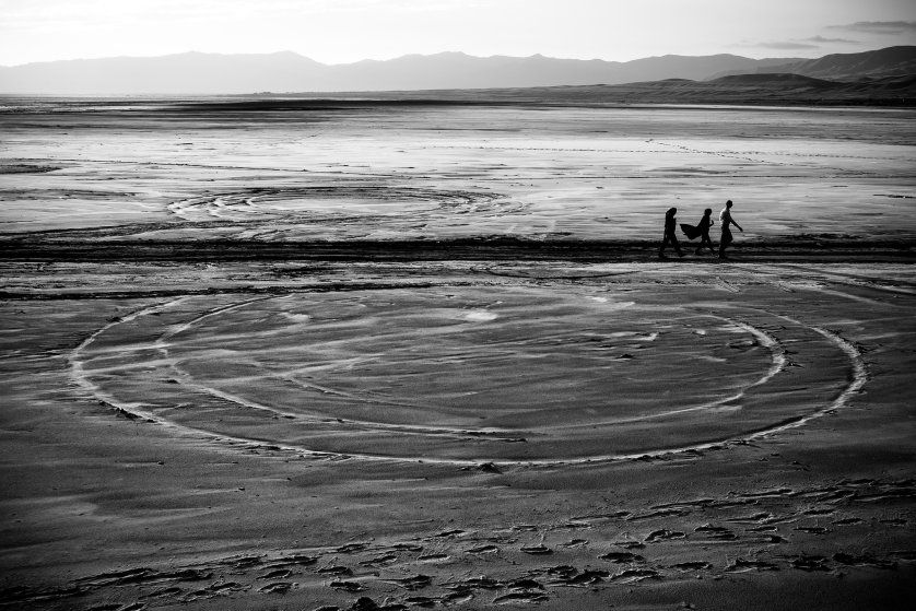 People walk on the dried Lake Urmia in northwestern Iran, near the Turkish border, which was one of the largest saltwater lakes in the Middle East. The lake has been shrinking over the last 20 years. This past summer algae and bacteria turned the water red. Image by Ako Salemi. Iran, 2016.