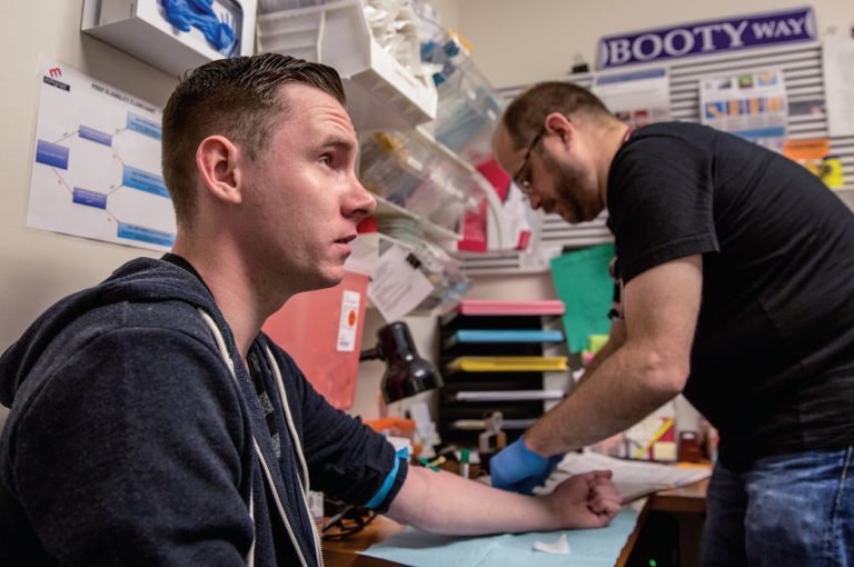 After this test showed Shane Ryan's blood was negative for the AIDS virus, Magnet's nurse practitioner Pierre-Cédric Crouch (background) offered him anti-HIV drugs to prevent infection. Image by Drew Bird for Jon Cohen's "End of AIDS" project. United States, 2015.
