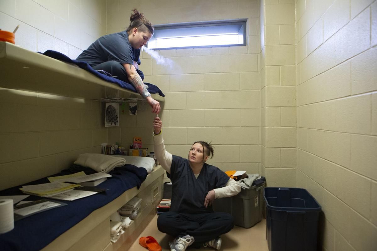 Tera Crowder, right, and her cousin by marriage, Michelle Blaney, share an e-cigarette while they were cellmates in the HARP program at the Chesterfield County Jail in 2018. "We have to have programs in jail available for people when they are ready [to quit]," said Dr. Mantovani Gay, the jail's medical director. Image by Julia Rendleman. United States, 2018.