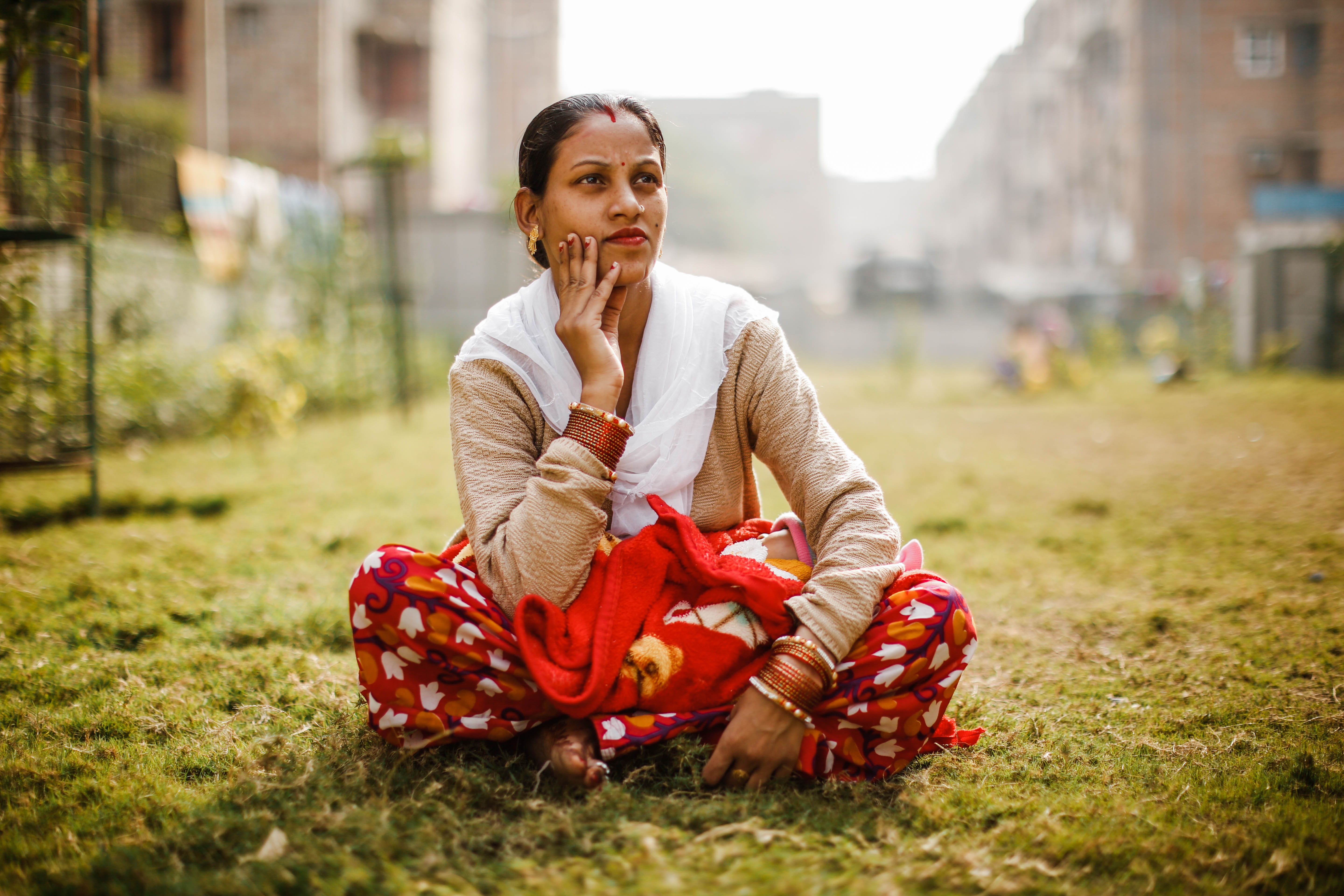A young Indian woman sits in a park in an relocation housing settlement in New Delhi. Image by Kiran Misra. India, 2018.