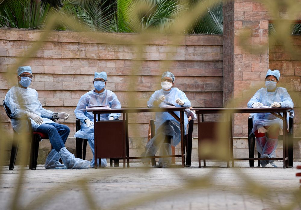 Medics arrive to take blood samples of residents of Spanish Garden residential complex after a COVID-19 positive case was detected in an apartment, in Guwahati. Image by David Talukdar / Shutterstock. India, 2020.