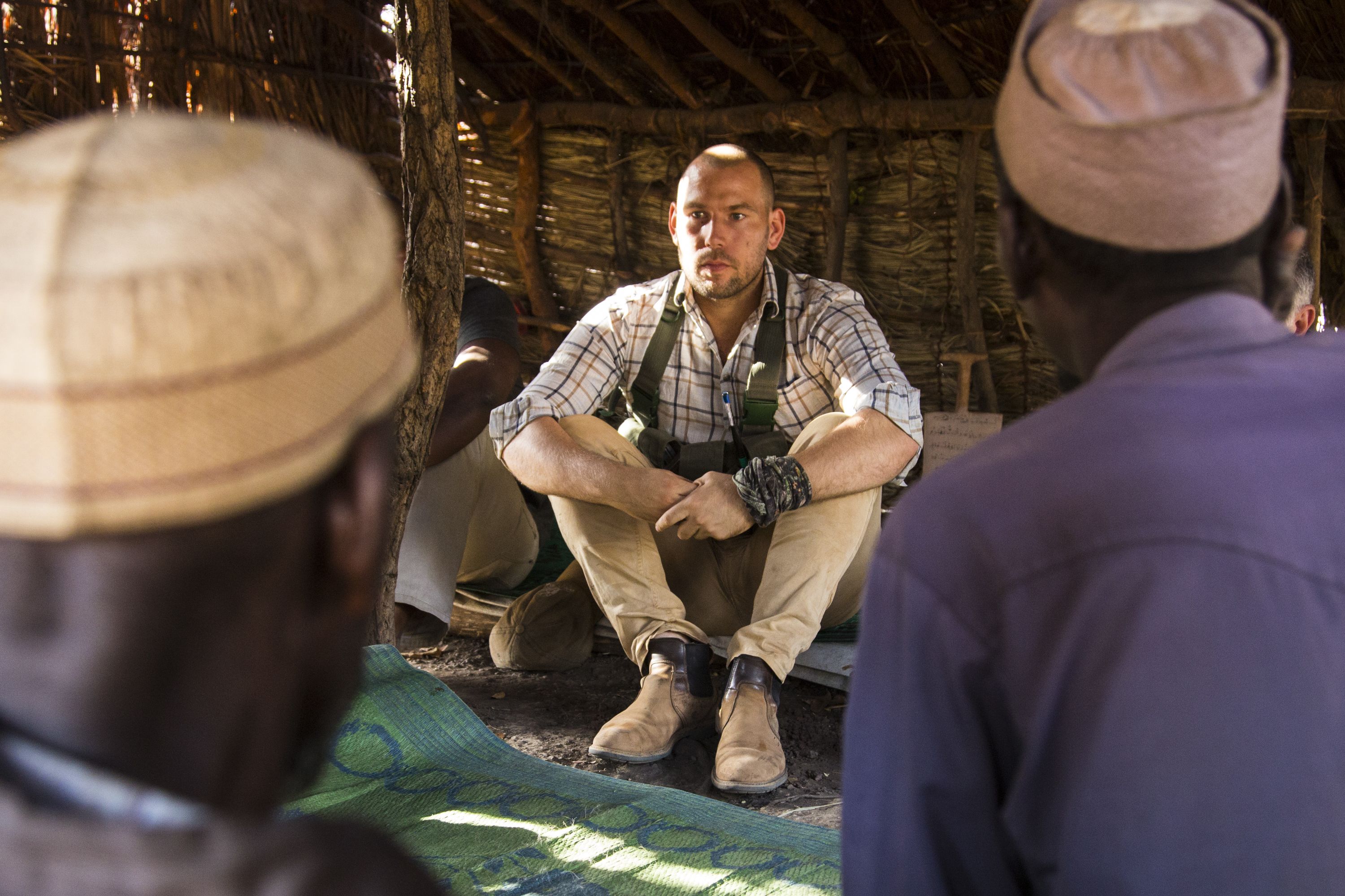 Chinko's park manager, David Simpson, speaks with elders of a community that was displaced by vicious fighting and is now sheltering inside the reserve. Image by Jack Losh. Central African Republic, 2018.