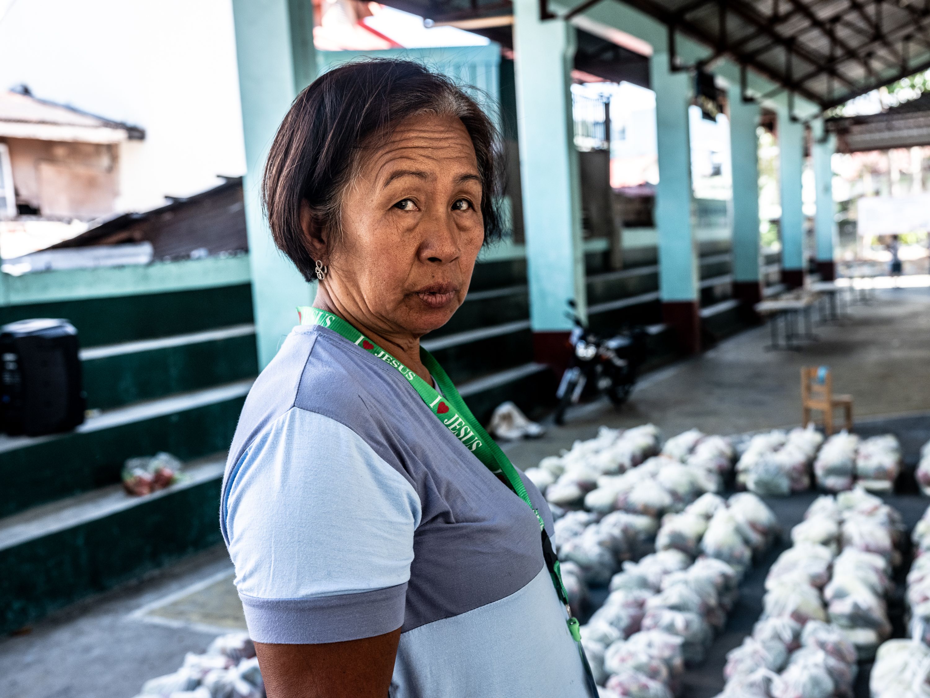 Reggie Renen, a volunteer health worker, rests after packing relief goods for the community. Image by Xyza Bacani. Philippines, 2020.