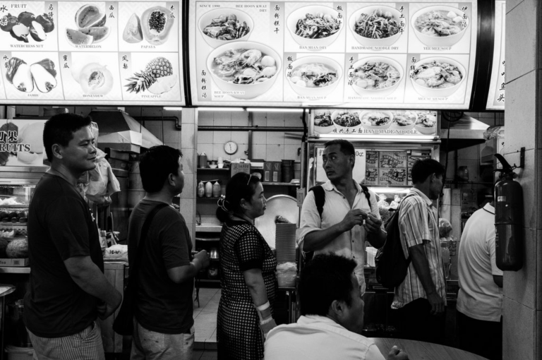 Xi Feng stands in the line with other Chinese migrant workers to get free meal. Image by Xyza Bacani. Singapore, 2017.
