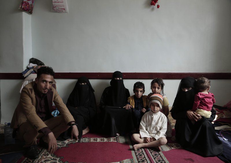 A family poses for a photograph in their room at a shelter for displaced persons in Ibb. Image by Nariman El-Mofty/AP Photo. Yemen, 2018.
