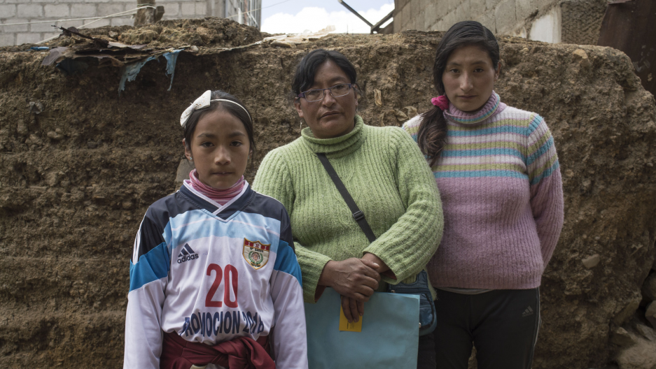 Sunmi (left) and Máyori (right) with their mother in their home. Sunmi was diagnosed by the Health Ministry in September 2015 with developmental disabilities, learning disability and chronic epistaxis (nosebleeds) from high levels of lead in her bloodstream. Image by Ricardo Martínez. Peru, 2017.