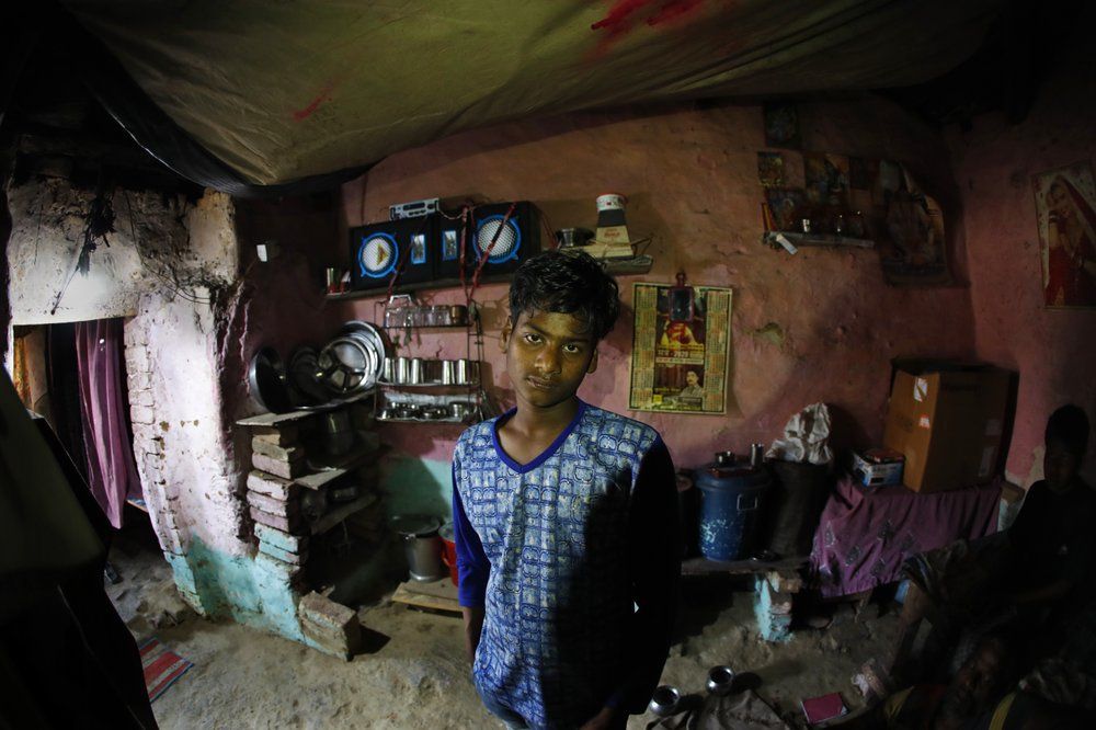 In this April 5, 2020, photo, Rajesh Dhaikar's son Deepak stands in their one small house in Prayagraj, India. Dhaikar has a small balloon stall in a nearby market, selling plastic bursts of red and blue and yellow one at a time, and rarely earning more than $2.50 a day. His wife, Suneeta, makes about $20 a month cleaning homes. They have five children, ranging in age and a bank account with about $6.50 in it. India has launched one of the most draconian social experiments in human history, locking down its entire population, including hundreds of millions of people who struggle to survive on a few dollars a day.