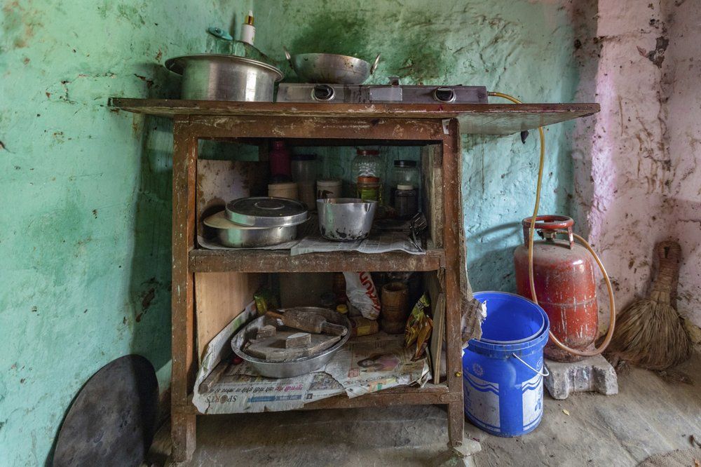 In this April 3, 2020, photo, Rajesh Dhaikar's kitchen corner is seen in his one room house in Prayagraj, India. Dhaikar has a small balloon stall in a nearby market, selling plastic bursts of red and blue and yellow one at a time, and rarely earning more than $2.50 a day. His wife, Suneeta, makes about $20 a month cleaning homes. They have five children, ranging in age and a bank account with about $6.50 in it. India has launched one of the most draconian social experiments in human history, locking down its entire population, including hundreds of millions of people who struggle to survive on a few dollars a day. Image by AP Photo/Rajesh Kumar Singh. India, 2020.