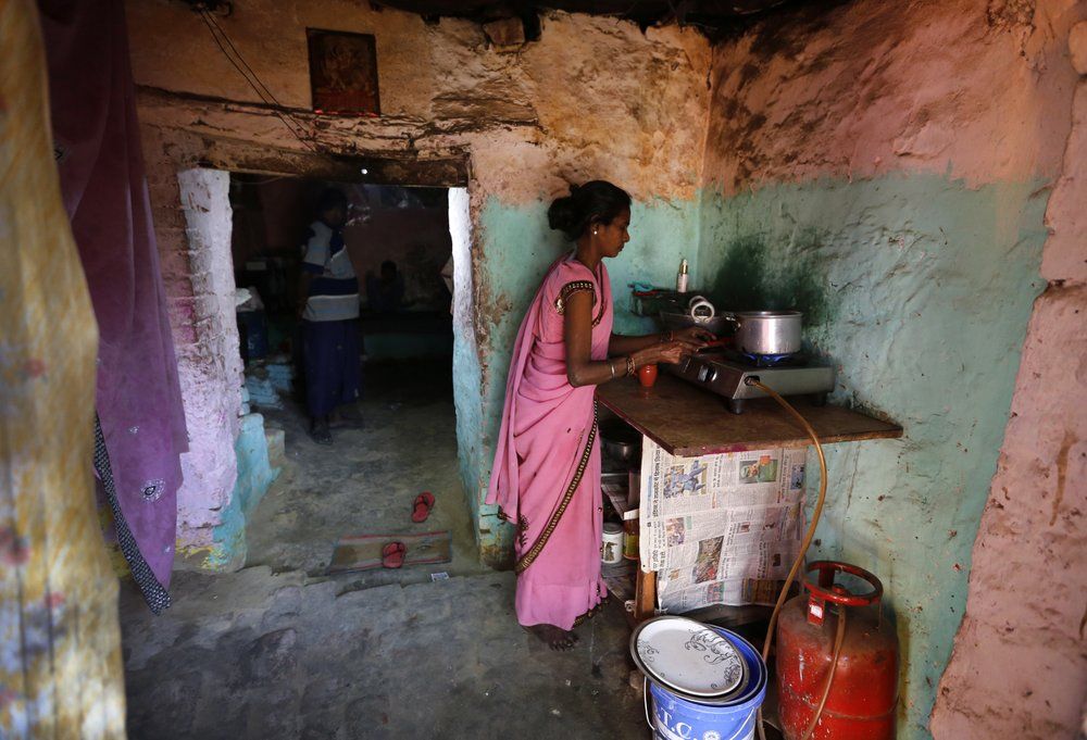 In this April 2, 2020, photo, Rajesh Dhaikar's wife Suneeta makes tea in her house in Prayagraj, India. Dhaikar has a small balloon stall in a nearby market, selling plastic bursts of red and blue and yellow one at a time, and rarely earning more than $2.50 a day. His wife, Suneeta, makes about $20 a month cleaning homes. They have five children, ranging in age and a bank account with about $6.50 in it. India has launched one of the most draconian social experiments in human history, locking down its entire population, including hundreds of millions of people who struggle to survive on a few dollars a day. Image by AP Photo/Rajesh Kumar Singh. India, 2020.