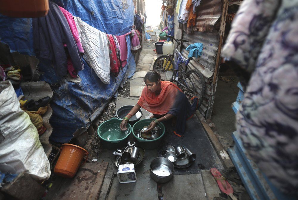 In this March 30, 2020, photo, Mina Ramesh Jakhawadiya's daughter Guddi Ramesh washes utensils outside her room in a slum in Mumbai, India. Jakhawadiya makes a living selling cheap plastic goods with her husband on the streets of Mumbai. For her, the order means 21 days in a 6-by-9 foot room with five people, no work, a couple days of food and very less cash. As governments around the world debate ways to slow the spread of coronavirus, India has launched one of the most draconian social experiments in human history, locking down its entire population, including hundreds of millions of people who struggle to survive on a few dollars a day. Image by AP Photo/Rajesh Kumar Singh. India, 2020.