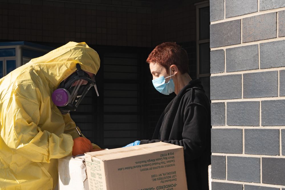 A men in a full protective suit delivers supplies to Elmhurst Hospital due to COVID-19 outbreak on March 26, 2020 in Queens neighborhood of New York City. Image by Ron Adar / Shutterstock. United States, 2020.