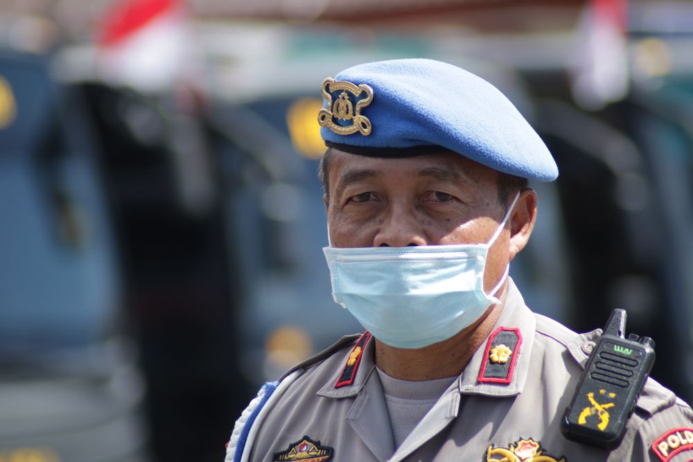 An Indonesian police officer wears a mask while on duty. Image by Herwin Bahar / Shutterstock. Indonesia, 2020.