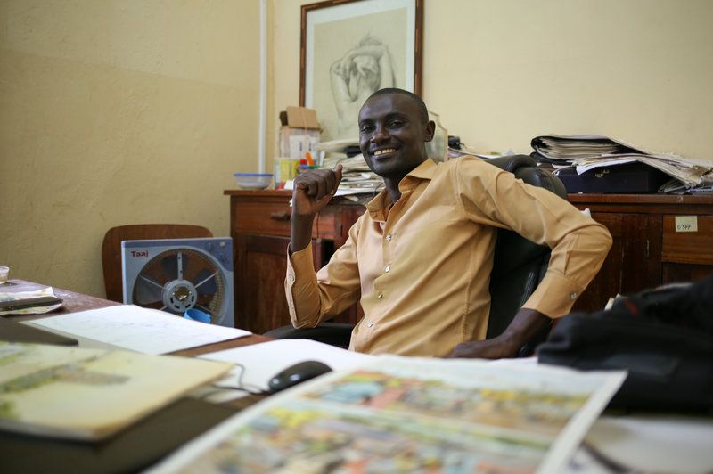 Didier Kassai uses comics to "transmit a message." His father opposed to a career in art until Kassai began earning money for his drawings. Here he sits in his office in Bangui, Central African Republic. Image by Cassandra Vinograd. Central African Republic, 2018.