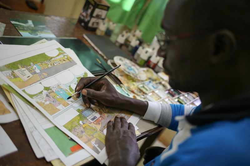 Didier Kassai works on an illustration in his office in Bangui, Central African Republic. Image by Cassandra Vinograd. Central African Republic, 2018.