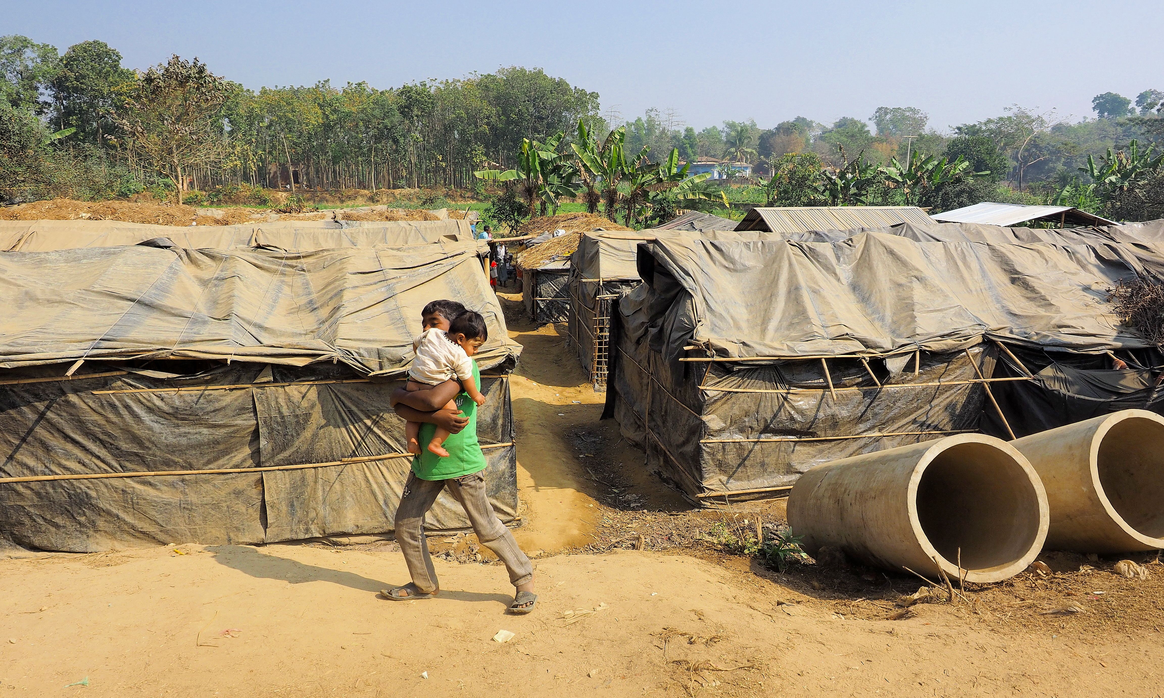 A boy carries his younger brother through the Kutapolong refugee camp. Image by Doug Bock Clark. Bangladesh, 2017. 