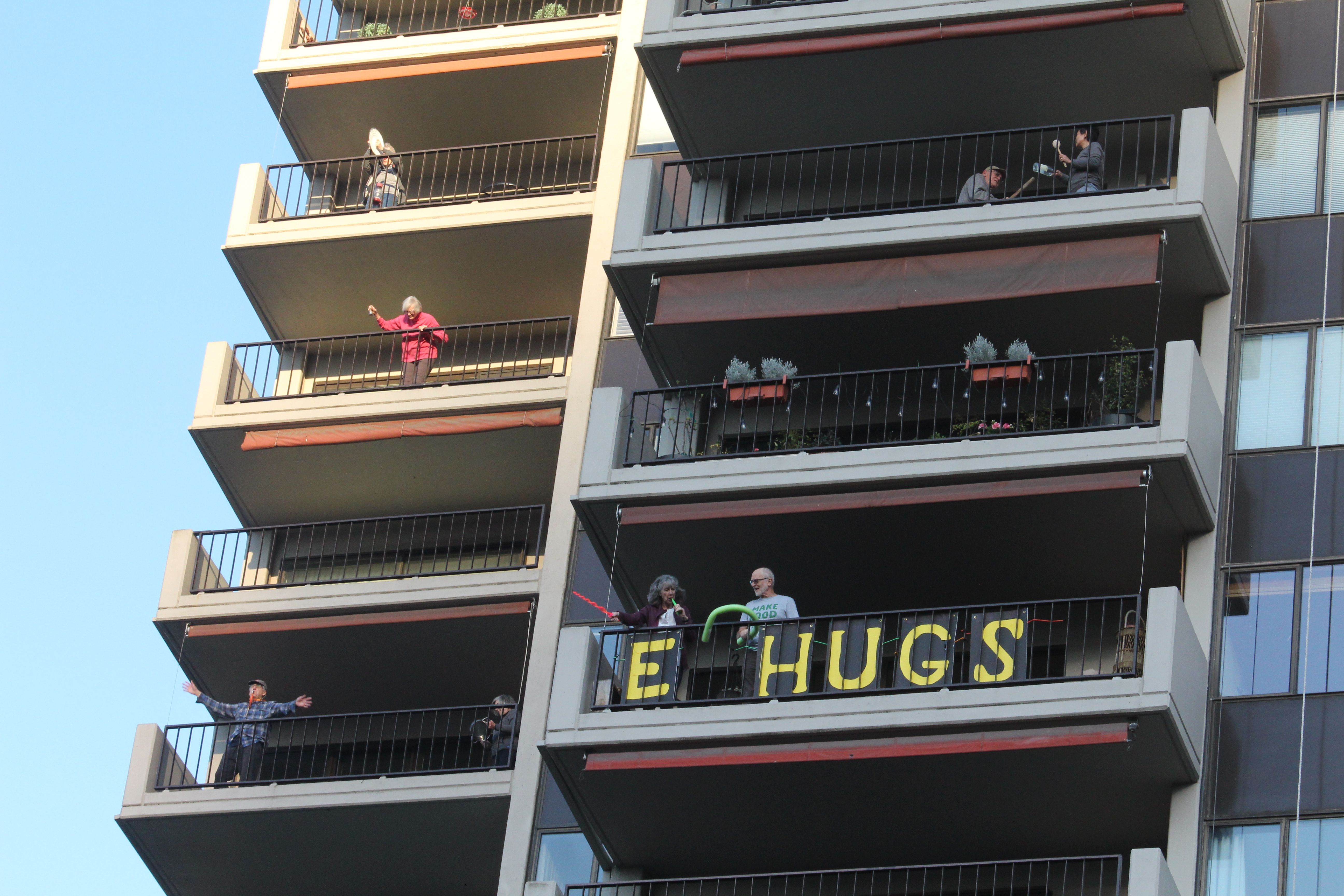 April 7, 2020 – One of the balconies of this building is decorated with a sign that reads, “E HUGS.” Image by Sarah Fahmy. United States, 2020.