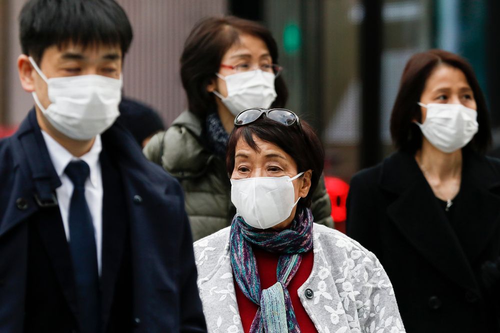 Pedestrians wearing surgical masks to prevent infectious diseases walk along the luxury area of Ginza. Japan has confirmed coronavirus infections cases in the country. Image by Shutterstock. Japan, 2020.