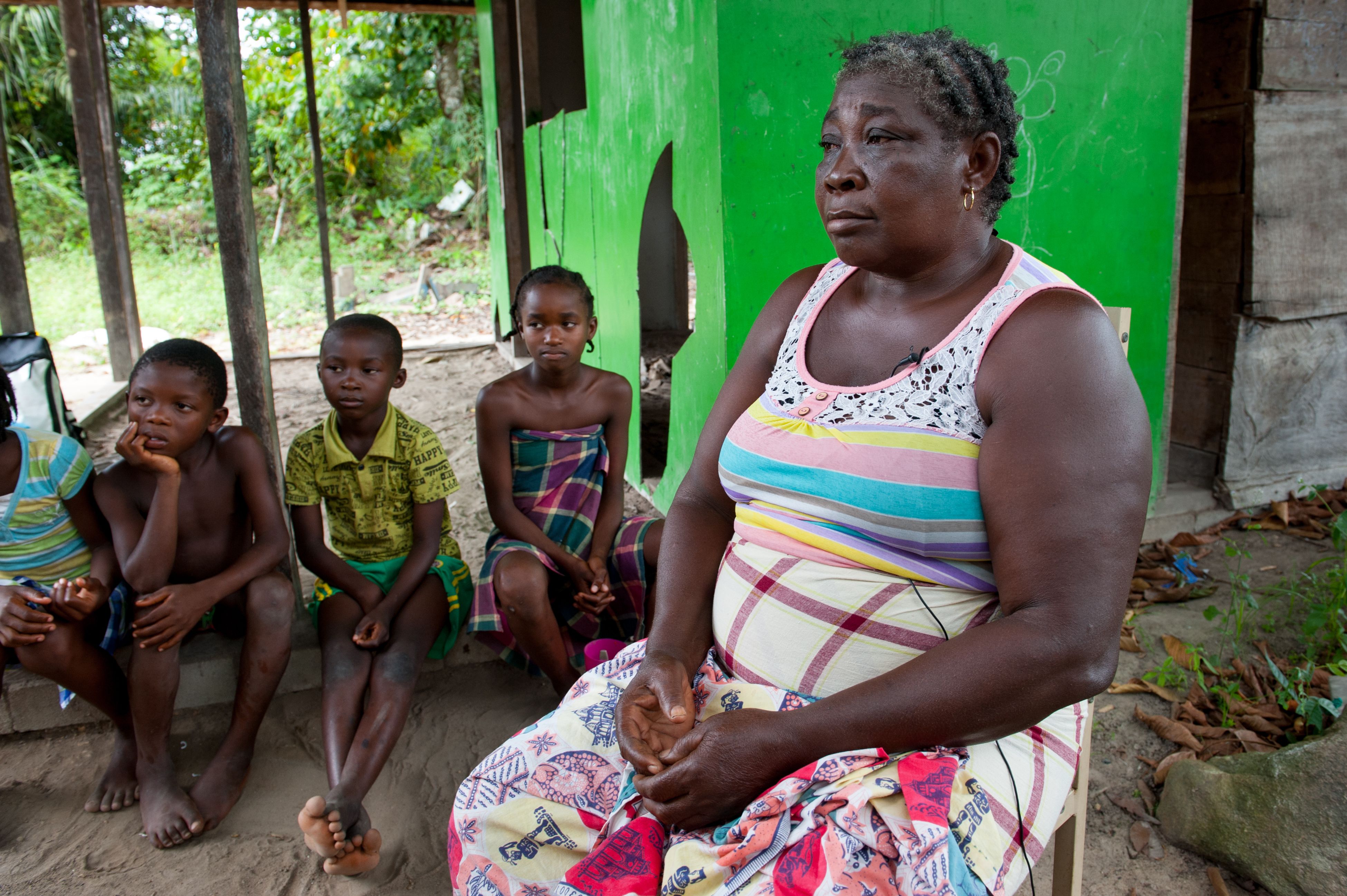 Emelien Adjako sits for an interview in her village of Kajapaati along the Suriname River on Tuesday, March 14, 2017. Adjako was one of those from over 40 Saamaka villages displaced by the flood waters caused by the formation of a reservoir with the construction of the Afobaka Dam. Built by Suralco to power a now defunct aluminum smelter, the dam now provides about half of Surinam's electricity, none of which has reached Adjako's replacement home. Image by Stephanie Strasburg/Pittsburgh Post-Gazette. Suriname. 