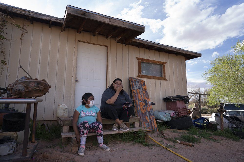 Angelina Dinehdeal wipes tears from her eyes as she sits with her 8-year-old daughter, Annabelle, on the family's compound in Tuba City, Ariz., on April 20, 2020. The family has been devastated by COVID-19. The Navajo reservation has some of the highest rates of coronavirus in the country. If Navajos are susceptible to the virus' spread in part because they are so closely knit, that's also how many believe they will beat it. Image by AP Photo/Carolyn Kaster. United States, 2020.