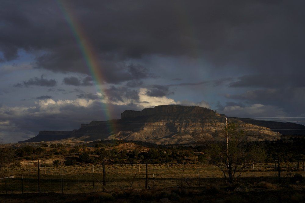 A rainbow is seen in the distance from the closed Chilchinbeto Church of the Nazarene in Chilchinbeto, Ariz., on the Navajo reservation on April 21, 2020. The reservation has some of the highest rates of coronavirus in the country. If Navajos are susceptible to the virus' spread in part because they are so closely knit, that's also how many believe they will beat it. Image by AP Photo/Carolyn Kaster. United States, 2020.