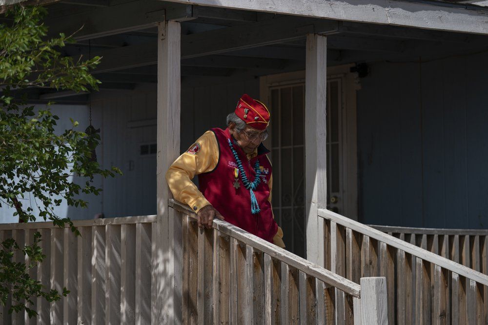 WWII veteran and Navajo Code Talker Peter MacDonald Sr. walks down the porch steps of his home on the Navajo reservation in Tuba City, Ariz., on April 28, 2020. The Navajo reservation has some of the highest rates of coronavirus in the country. If Navajos are susceptible to the virus' spread in part because they are so closely knit, that's also how many believe they will beat it. Image by AP Photo/Carolyn Kaster. United States, 2020.
