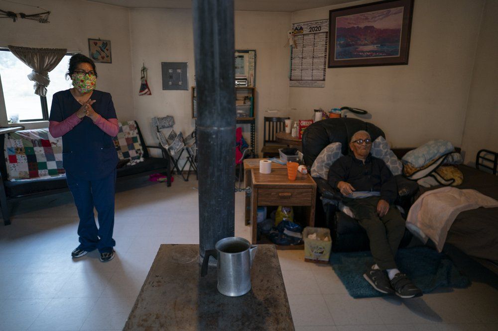 Mabel Charley, left, applies hand sanitizer as she arrives to care for her home-bound uncle in his hogan, a traditional Navajo dwelling, in Chilchinbeto, Ariz., on the Navajo reservation on April 21, 2020. The Navajo reservation has some of the highest rates of coronavirus in the country. If Navajos are susceptible to the virus' spread in part because they are so closely knit, that's also how many believe they will beat it. Image by AP Photo/Carolyn Kaster. United States, 2020.