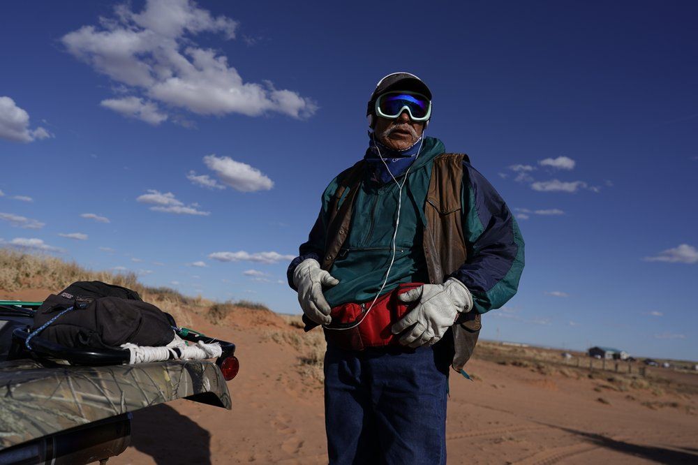 Navajo shepherd Leslie Dele stands next to his all-terrain vehicle as he waits for the sheep to come in on his family ranch outside Tuba City, Ariz., on the Navajo reservation April 22, 2020. The Navajo reservation has some of the highest rates of coronavirus in the country. If Navajos are susceptible to the virus' spread in part because they are so closely knit, that's also how many believe they will beat it. Image by AP Photo/Carolyn Kaster. United States, 2020.