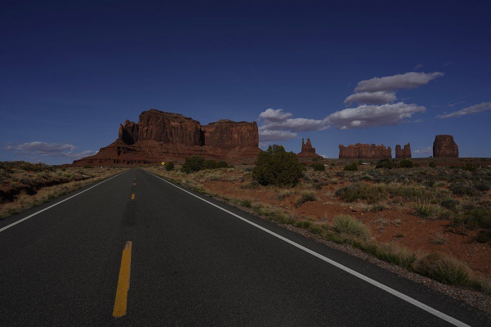 This April 23, 2020 photo shows an empty Interstate 163 in Oljato-Monument Valley, Utah, on the Navajo reservation. To help prevent the spread of COVID-19, the Navajo Monument Vally Tribal Park is closed. Image by AP Photo/Carolyn Kaster. United States, 2020.