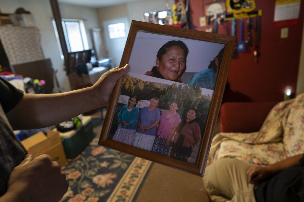 Eugene Dinehdeal holds photos of family members, including Eva Dinehdeal at top, at the Dinehdeal family compound in Tuba City, Ariz., on the Navajo reservation on April 20, 2020. Eva Dinehdeal died of COVID-19 on April, 11, 2020. Image by AP Photo/Carolyn Kaster. United States, 2020.