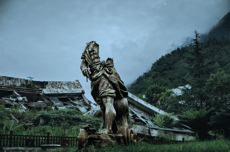 A broken statue of Da Yu, the god-king who tamed the long-term flooding of China’s rivers, in front of the collapsed Beichuan county-government building. Both were damaged in the 2008 earthquake. Image by Sim Chi Yin/VII Photo. China, 2015.