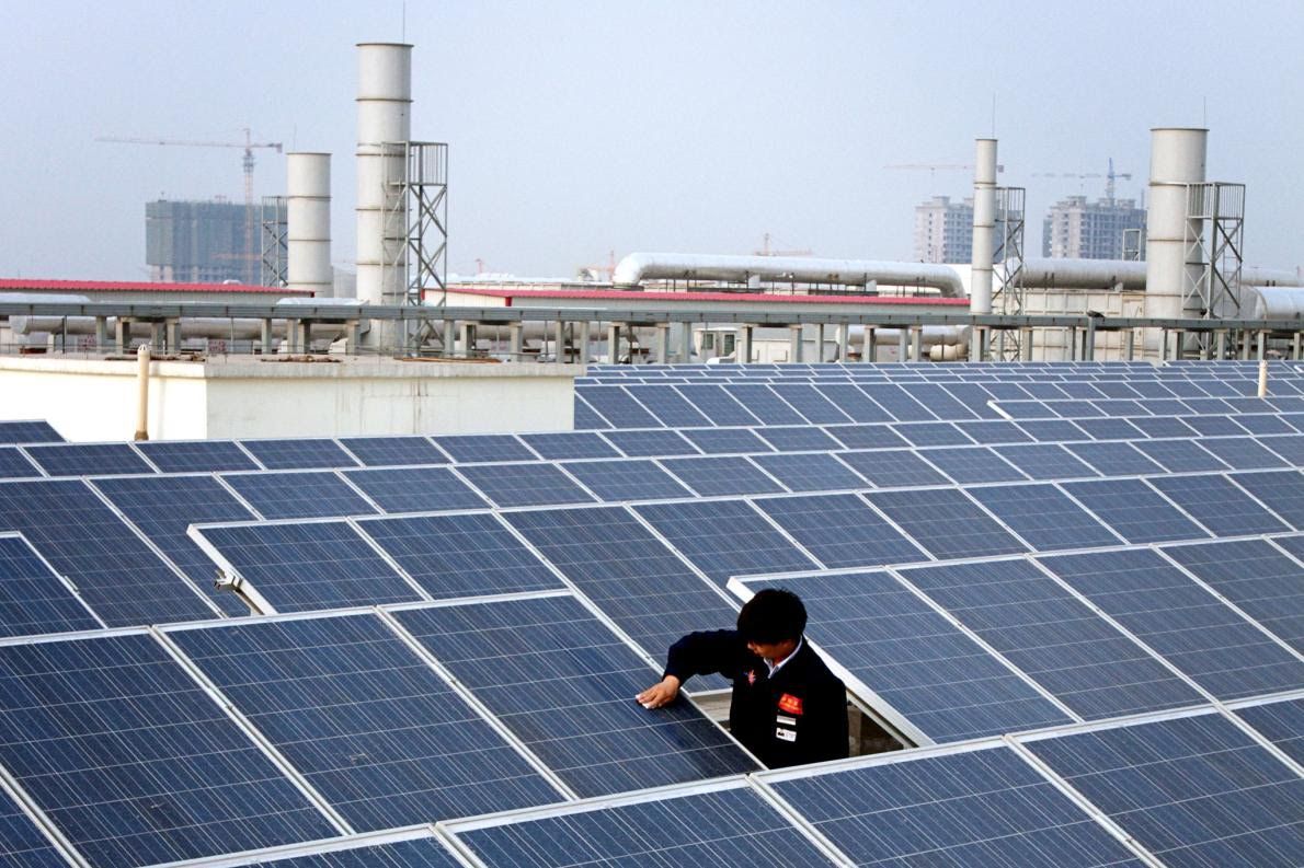 A worker cleans a solar panel on top of a factory building in Baoding City. China is installing a soccer field's worth of solar panels every hour. Image by Sean Gallagher. China, 2017.
