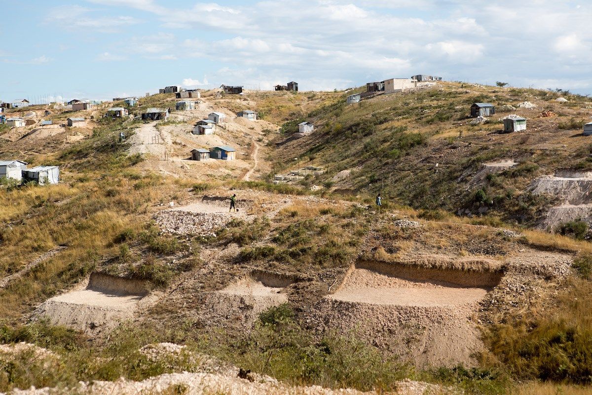 A man works to level a plot of land in order to begin building a home in the Canaan settlement. Image by Allison Shelley. Haiti, 2018.