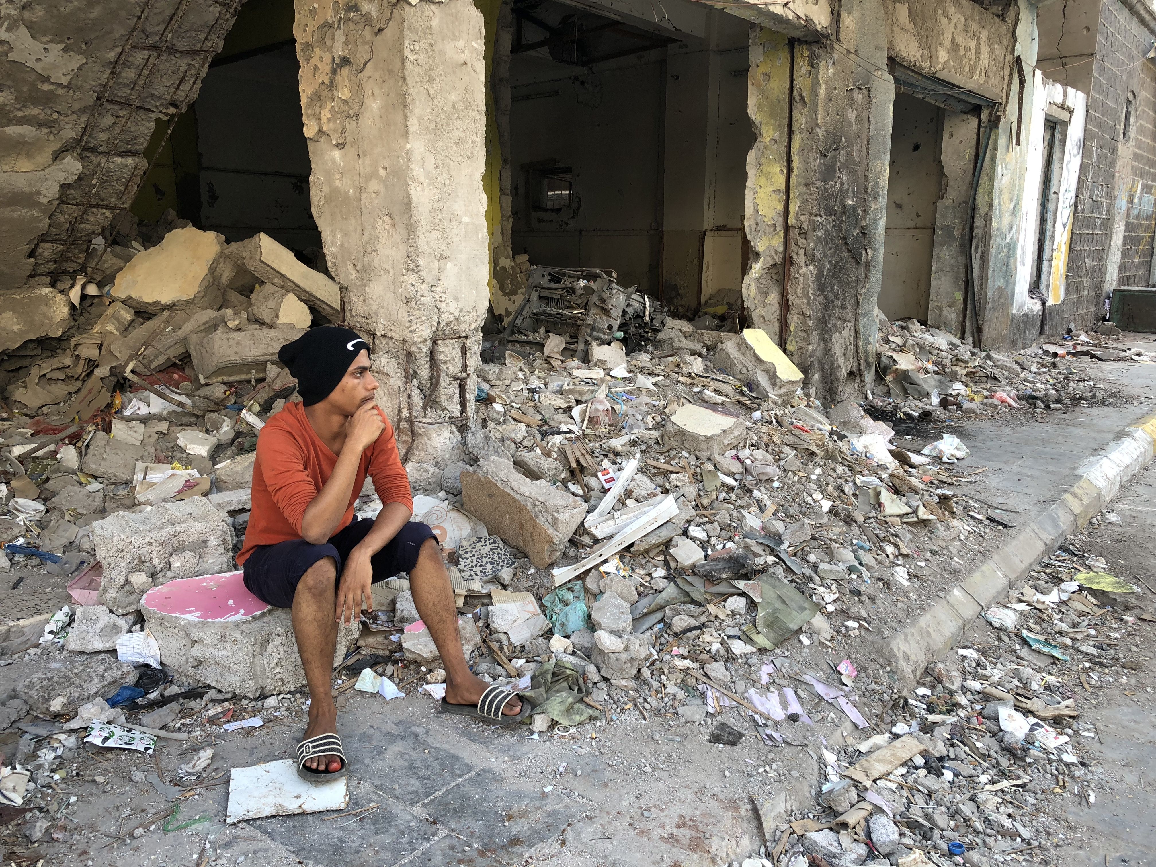 Moaad sits in the rubble of his home in the Kraytar district of Aden, hit so hard during the 2015 battle between government forces and Houthi rebels. Three years after the battle, this neighborhood, like so many in Aden, has never been rebuilt. Image by Marcia Biggs. Yemen, 2018.
