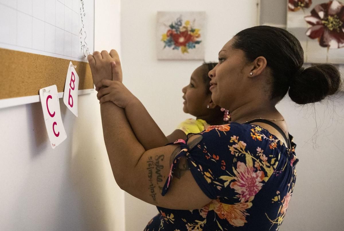 Tyra Johnson helps her daughter Madison Hundley, 4, write "chair" on the whiteboard during a home-school lesson at her house in St. Louis. Johnson has set up a strict daily schedule for distance learning. Image by Colter Peterson / Post-Dispatch. United States, 2020.