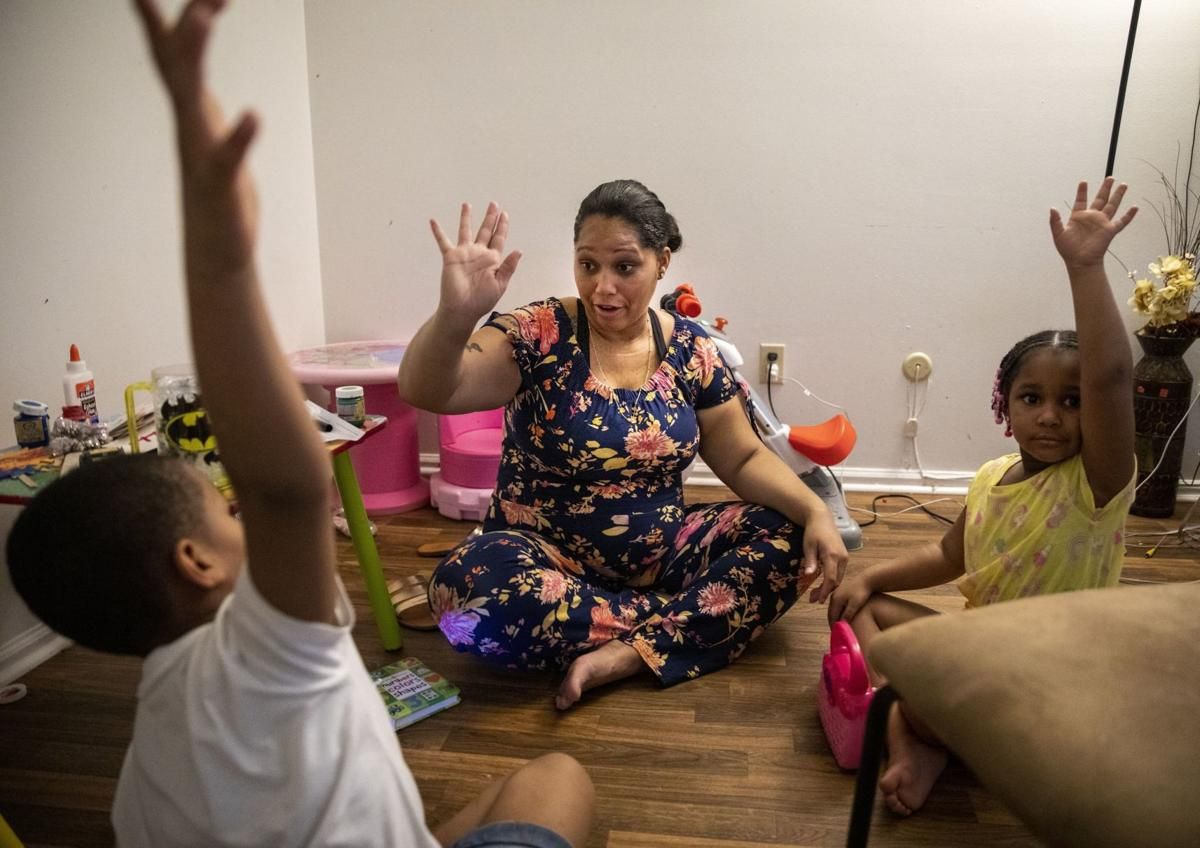 Tyra Johnson asks her kids, Madison Hundley, right, and Meegale Hundley, to raise their hands in order to get their attention during a home-school lesson. "You have to be consistent with kids," she said. "So they don't slip through the cracks." Image by Colter Peterson / Post-Dispatch. United States, 2020.