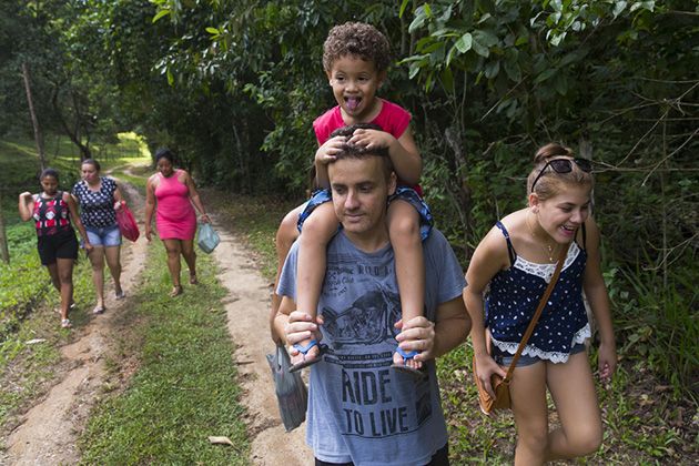 Alessandro Valenca, 38, carries his son, Davi Luiz, on his shoulders while walking to a gathering with his extended family at his parent's home in the village of Córrego Da Luz, Brazil. Image by Mark Hoffman. Brazil, 2017.
