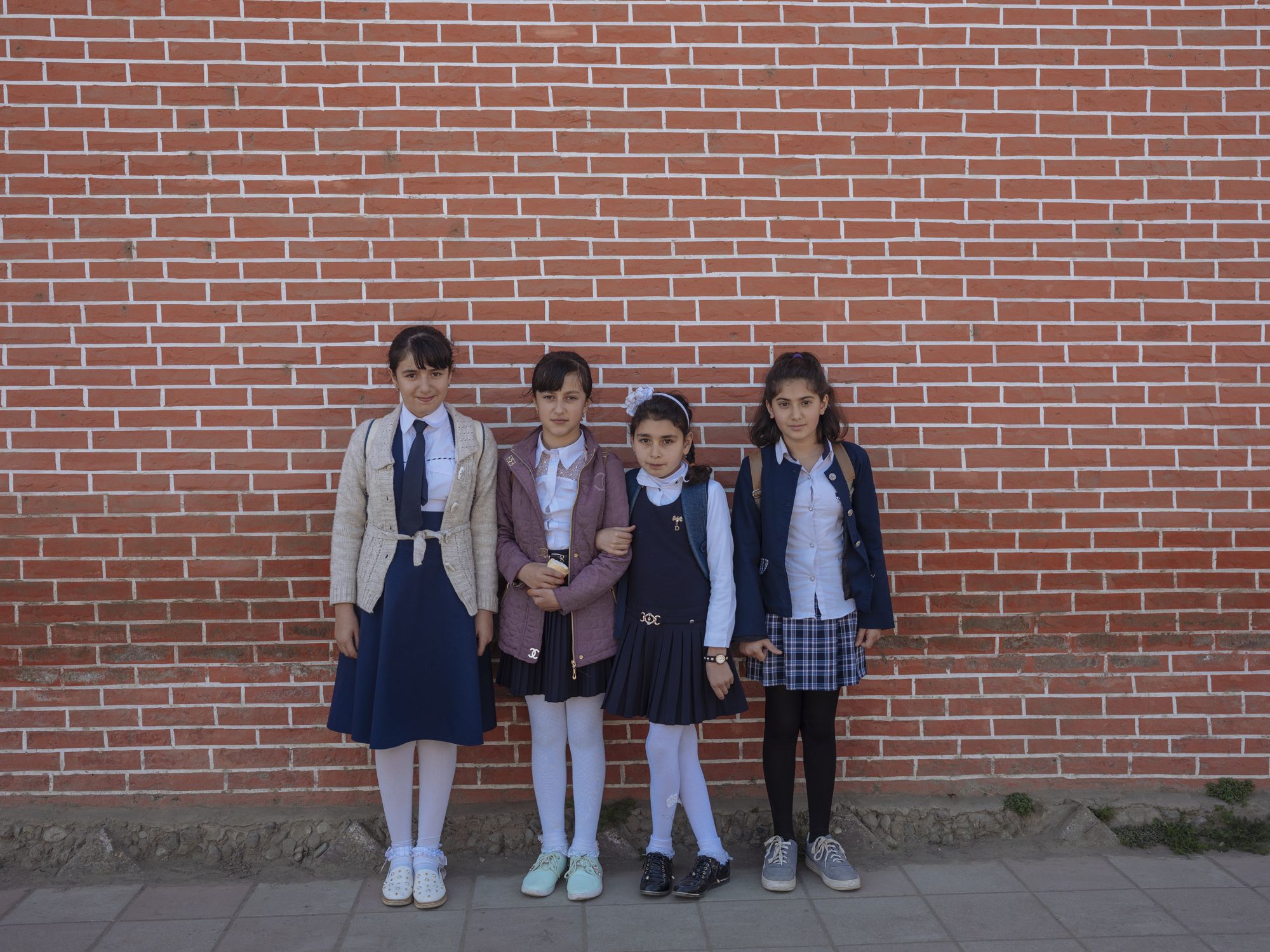Girls pose after school in Kakalos village. Kakalos is a modern village, where girls are able to go to school. But outside of this town, in more isolated villages, the Soviet-era education system is obsolete and ill-equipped to prepare youth for the society of today. Azerbaijan still suffers from too many traditions that often undermine education, especially that of young girls. Some girls are so depressed with the education they receive that they give up on it, and prefer getting married. Image by Emin Ozmen / Magnum Photos. Azerbaijan, 2018.