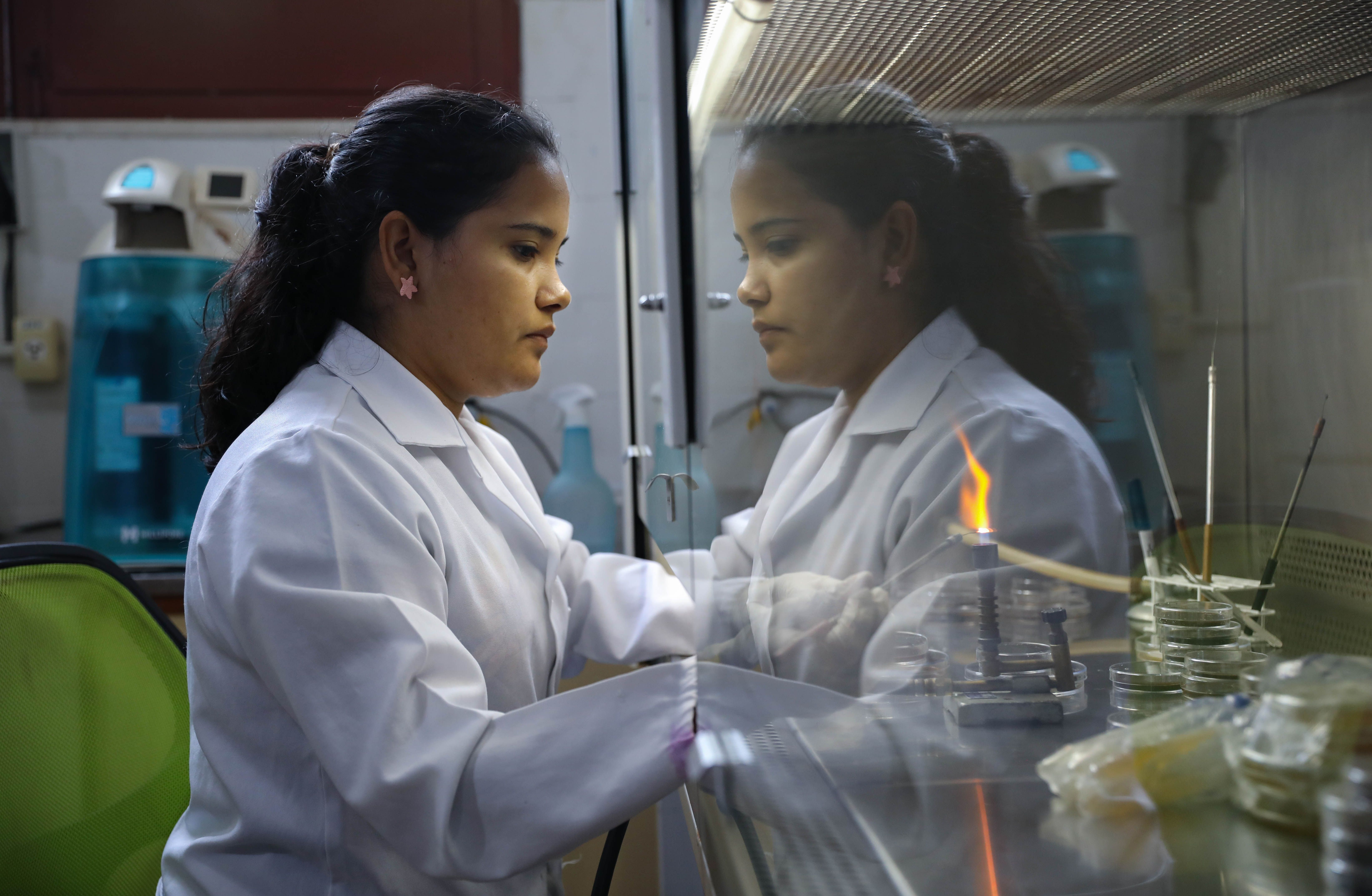 Naila Cruz, a biomedical doctorate student, uses a Bunsen burner to sterilize medical equipment used while studying mycobacterium leprae—the bacteria that causes leprosy—in the Laboratory of Dermatology-Immunology. Image by Anton L. Delgado. Brazil, 2020.