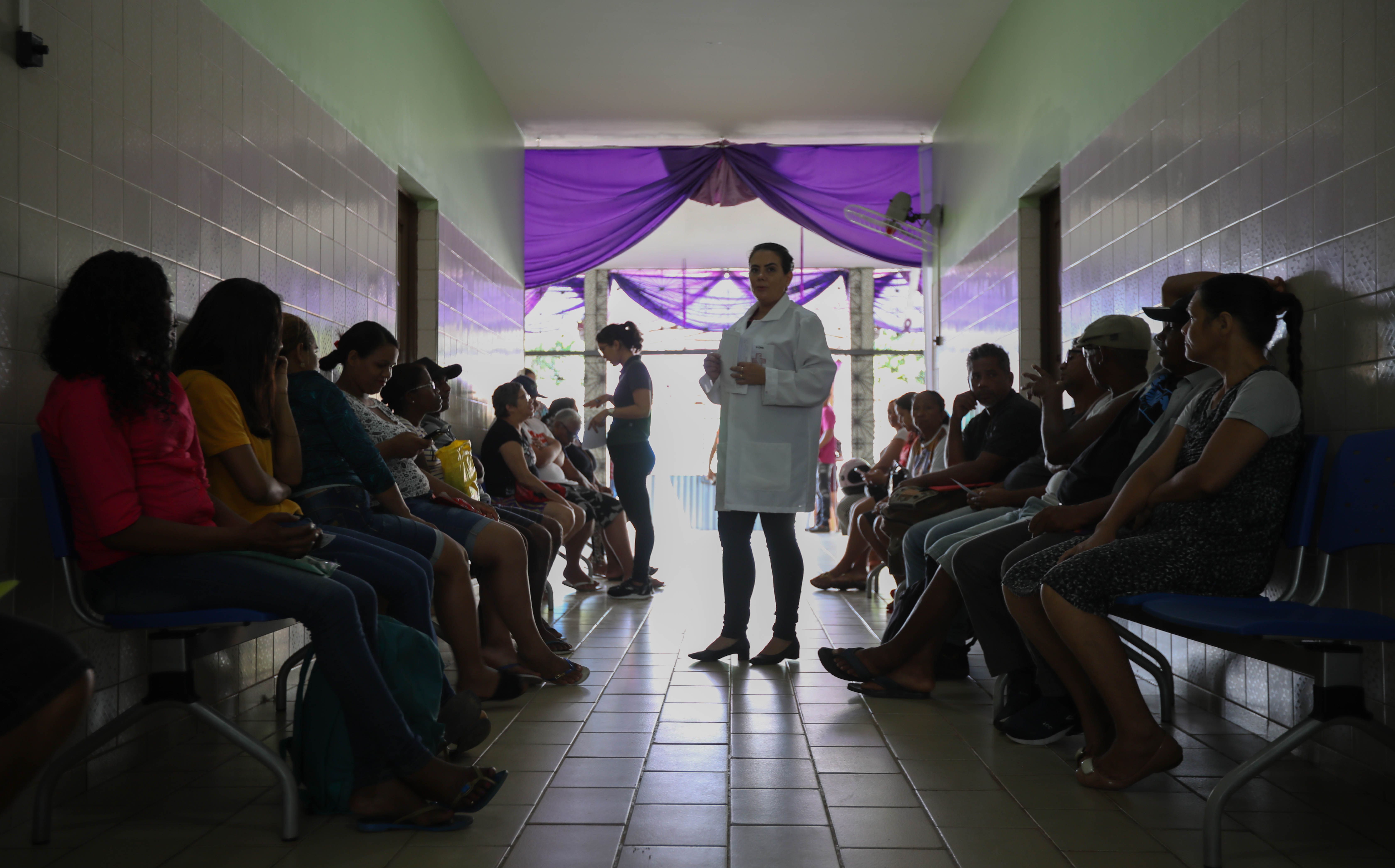 Dozens of people line the hallways of the Center of Dermatology in Marituba during Leprosy Awareness Month in January. Erika Jorge, a member of the Laboratory of Dermatology-Immunology, is in charge of shepherding patients from corridors to examination rooms. Image by Anton L. Delgado. Brazil, 2020.