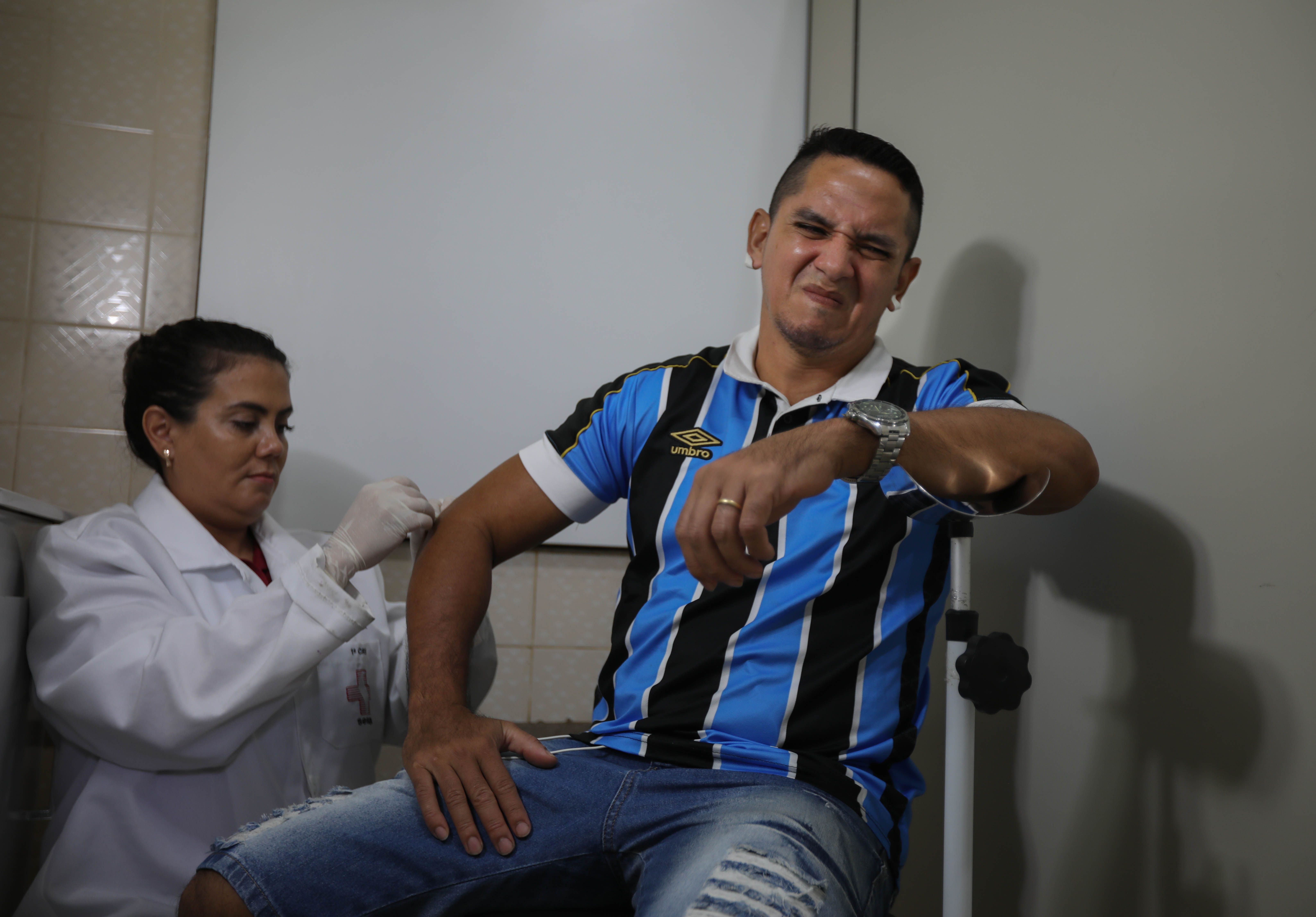 Fernando Macedo, 40, grimaces as Erika Jorge, a member of the Laboratory of Dermatology-Immunology, takes skin samples from his elbow during his Slit-skin smear examination. Image by Anton L. Delgado. Brazil, 2020.