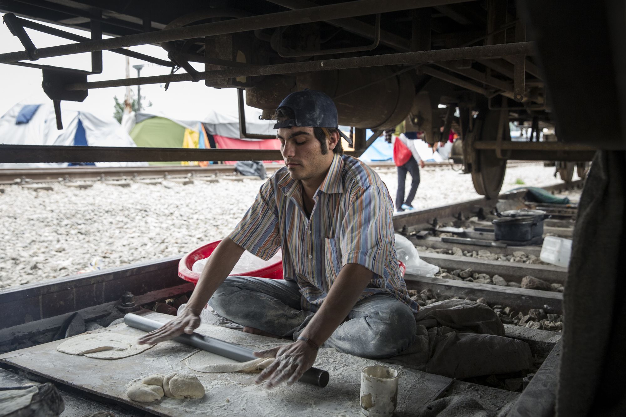 Syrian man bakes bread under train car 