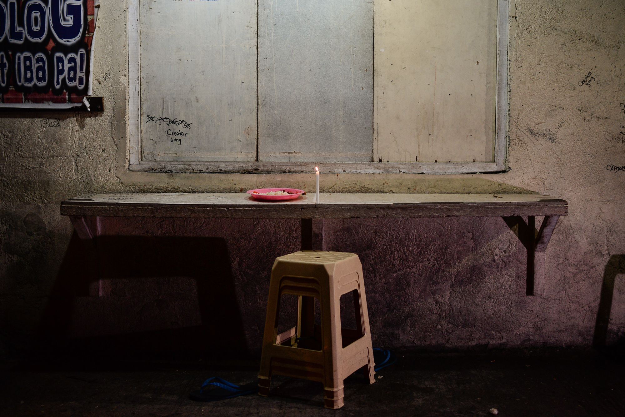 A candle is left where Alvin Jhon Mendoza, twenty-three, was killed by riding-in-tandem gunmen while eating at a canteen near his home. Image by Eloisa Lopez. Manila, 2016.