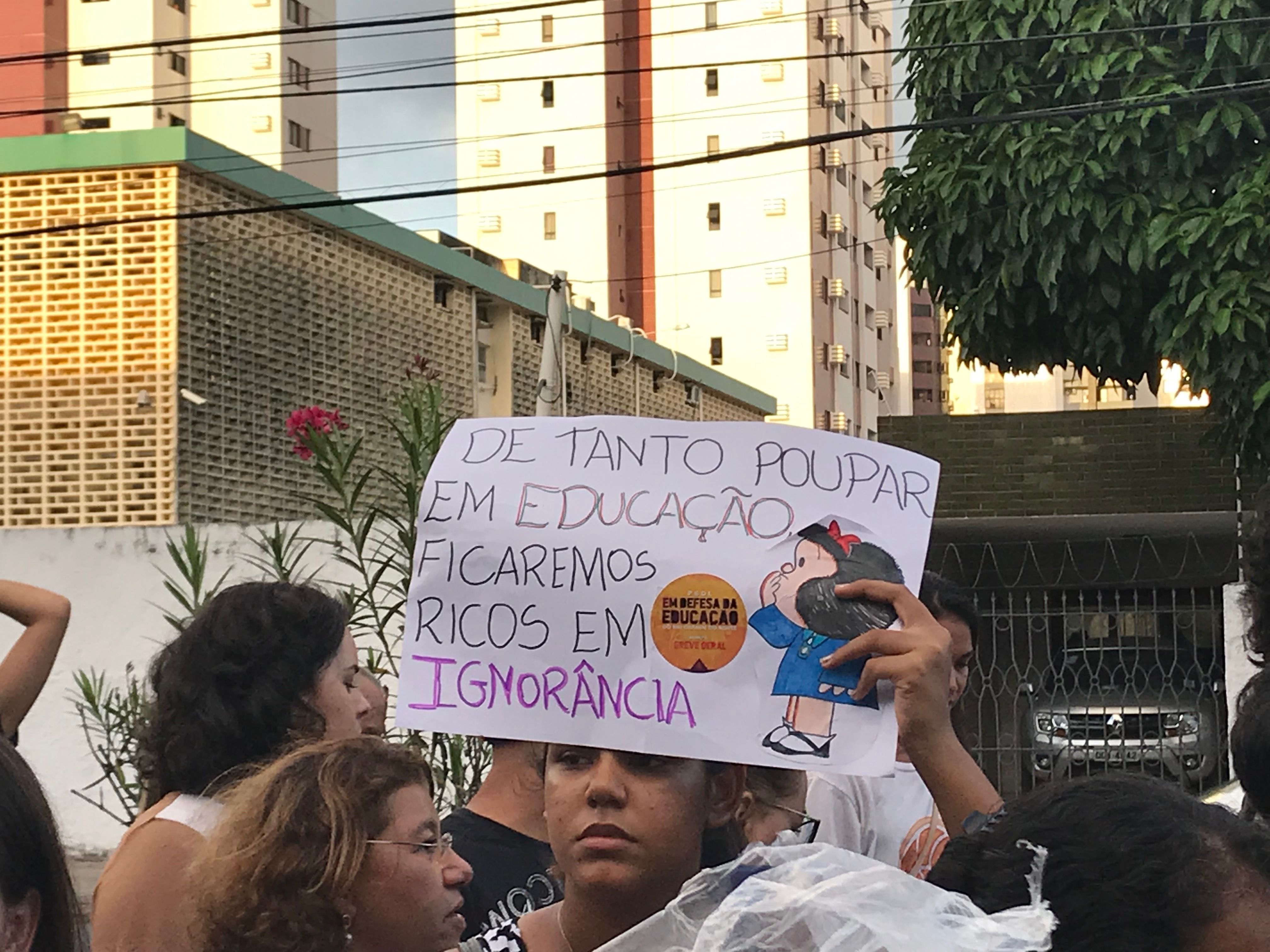 A protester's sign reads “For as long as we save spending on education, we will be rich in ignorance.” Brazil, 2019. Image by Rafael Lima.