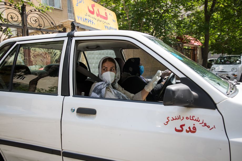 Maryam Rezaie, 58, works as a driving instructor in the capital Tehran and supports her family financially. But wearing a mask and gloves along with the headscarf is an additional limitation in the car. Maryam is afraid of getting infected at work. Image by Mehdi Fazlollahi / NVP Images. Iran, 2020.