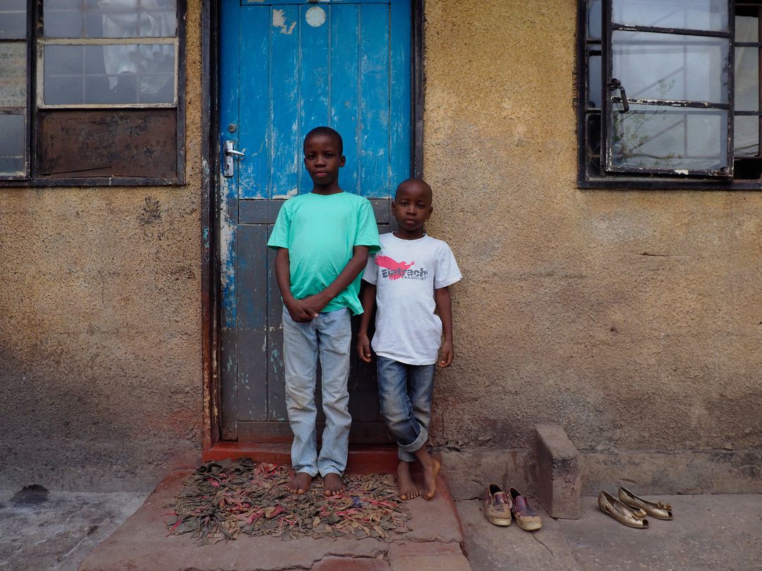 Lead poisoning victims: Gift Chilufya (green shirt), 10, right, and his brother, Martin Cilufya, 7, left. Gift and Martin have tested for high blood lead levels. They live in Chowa, a poor neighborhood next to the closed lead mine. Image by Larry C. Price. Zambia, 2017. 