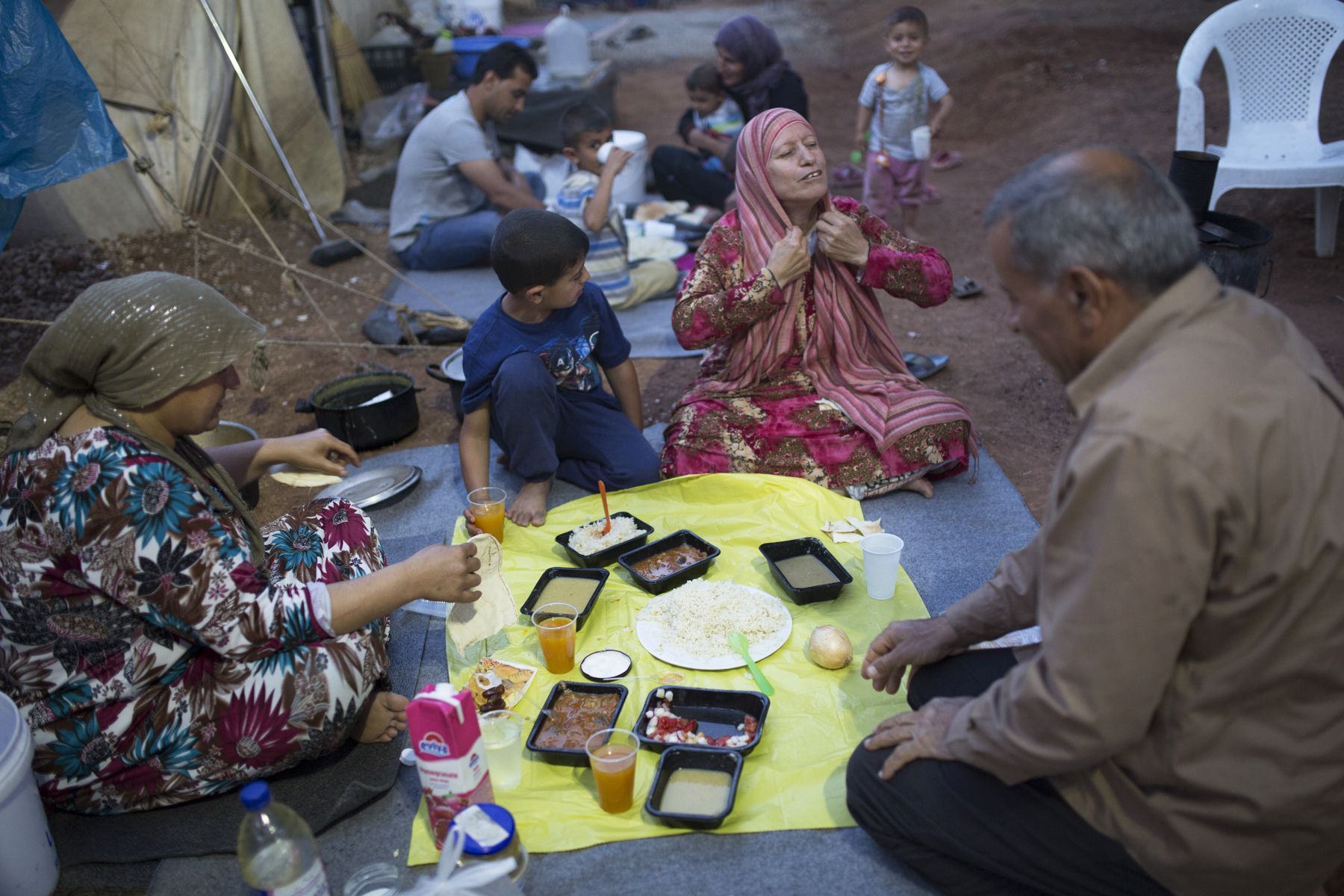 Family breaking Ramadan fast on the ground near tent 