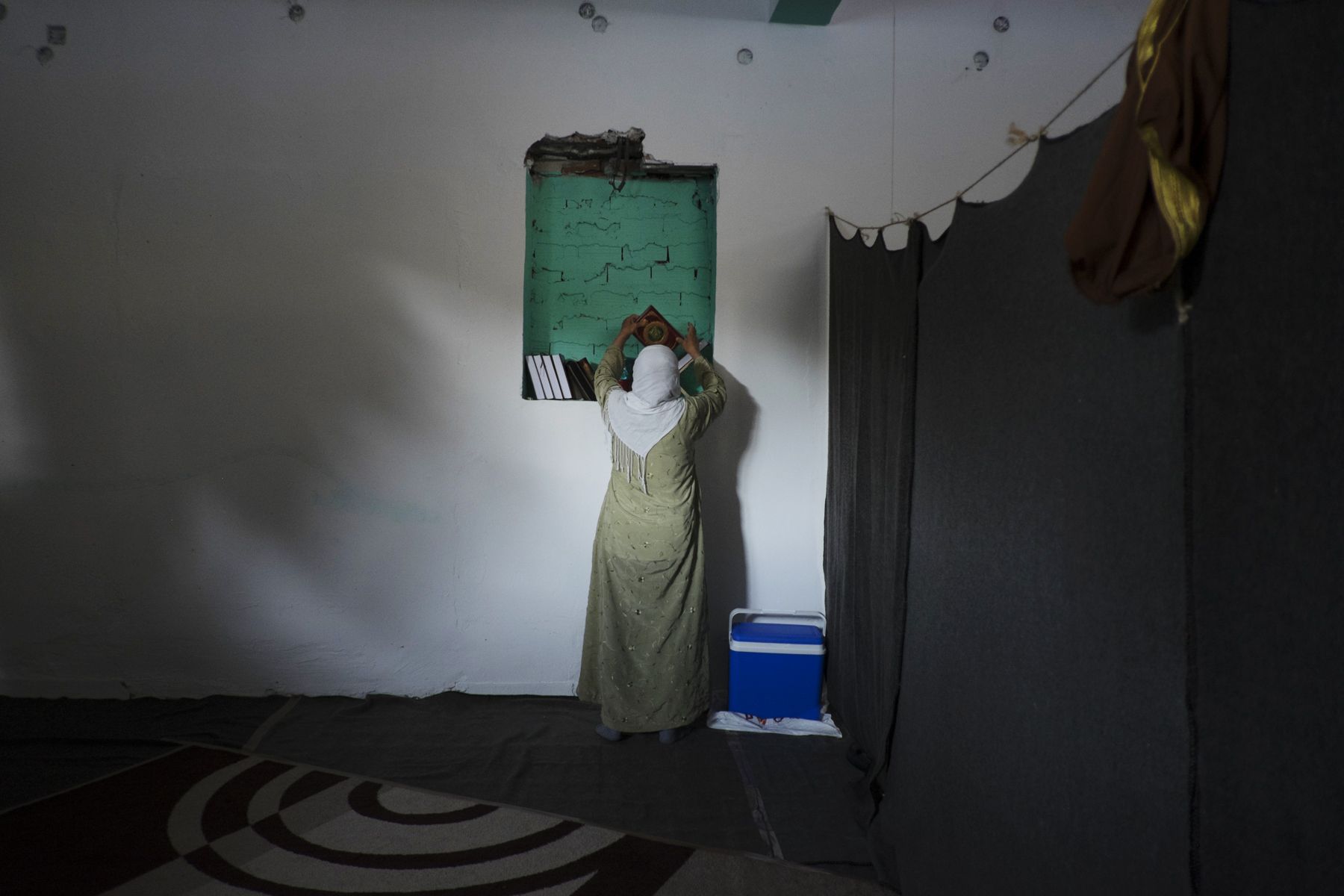 Woman reaching for Koran inside makeshift mosque 