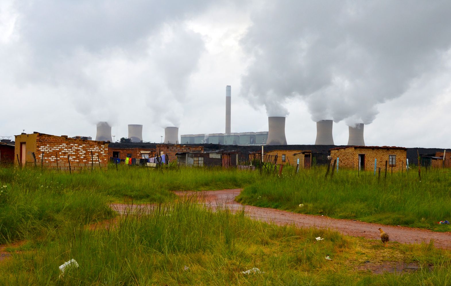 Duvha Power Station looms over the Masakhane informal settlement near eMalahleni in Mpumalanga. In 2015, the government pledged R18-billion to assist or relocate 15 mining-affected communities, including Masakhane. Image by Mark Olalde. South Africa, 2017.